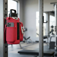 red crossbody bag attached to a metal bar in a gym setting