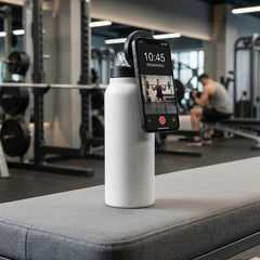 Smartphone with a fitness app displayed on a water bottle in a gym setting